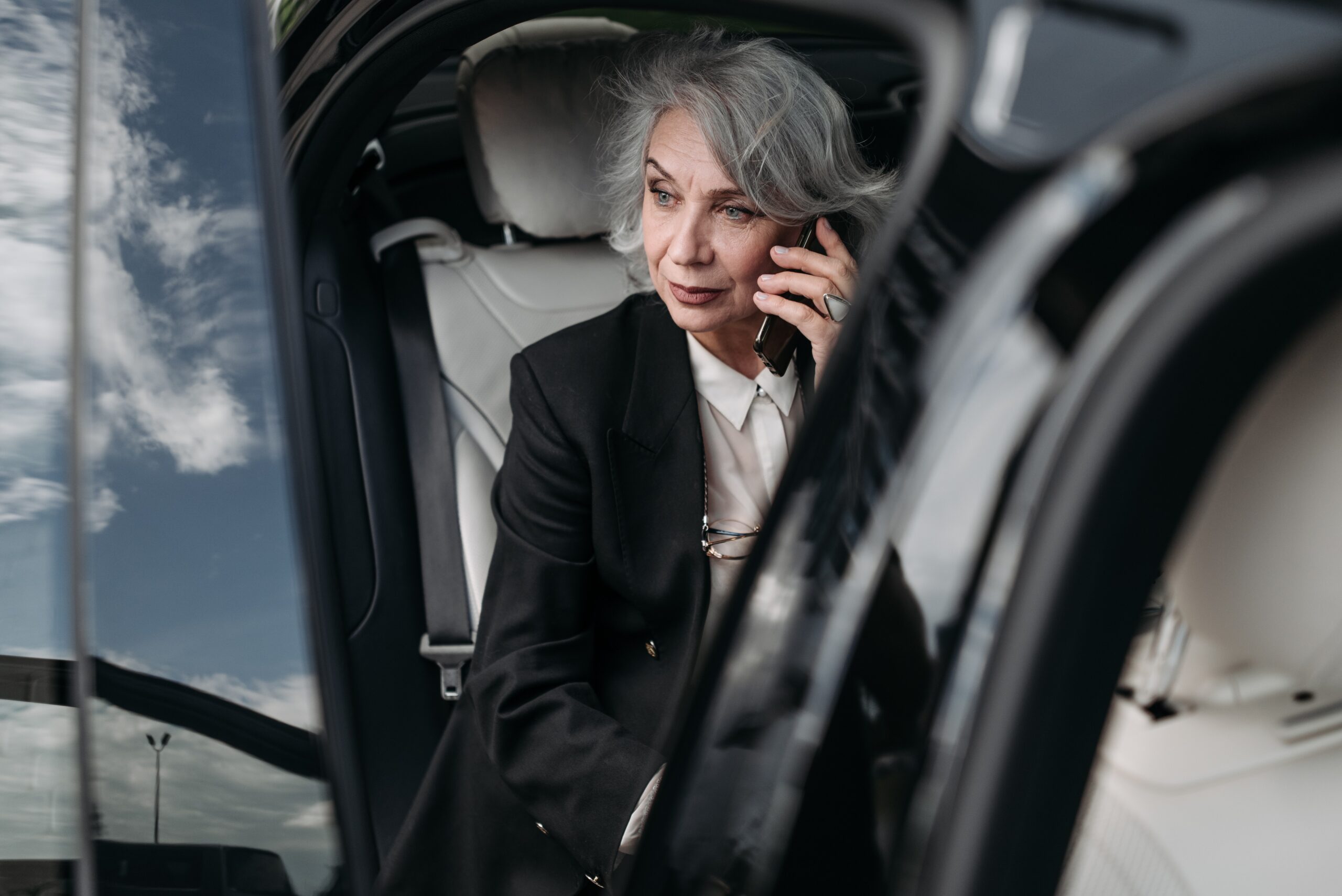 grey-haired woman listening to mobile phone in car