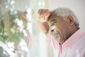 older man resting head against window