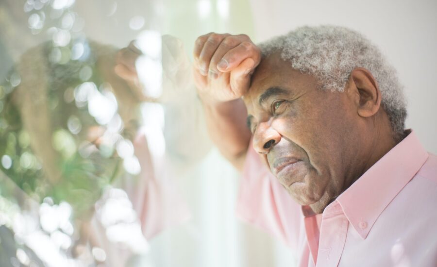 older man resting head against window