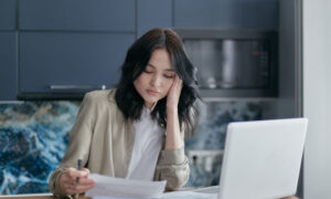 A woman at her computer, reading her bills.