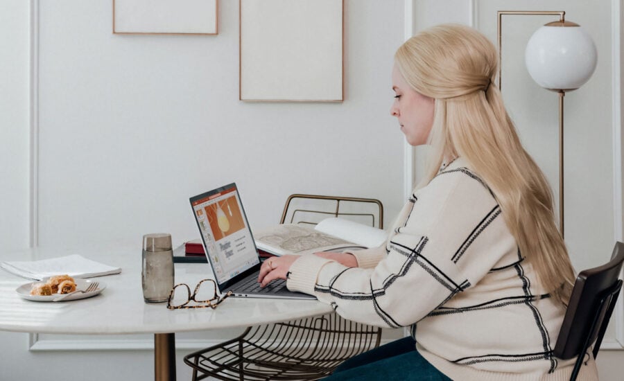 A woman doing her taxes on her laptop, sitting in her kitchen