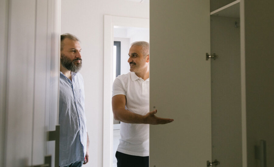 Two men looking around an empty room that's ready to be moved into.