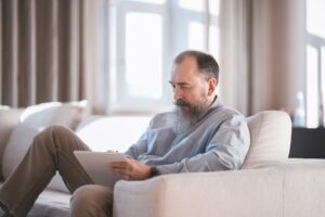 grey-haired man studying on couch