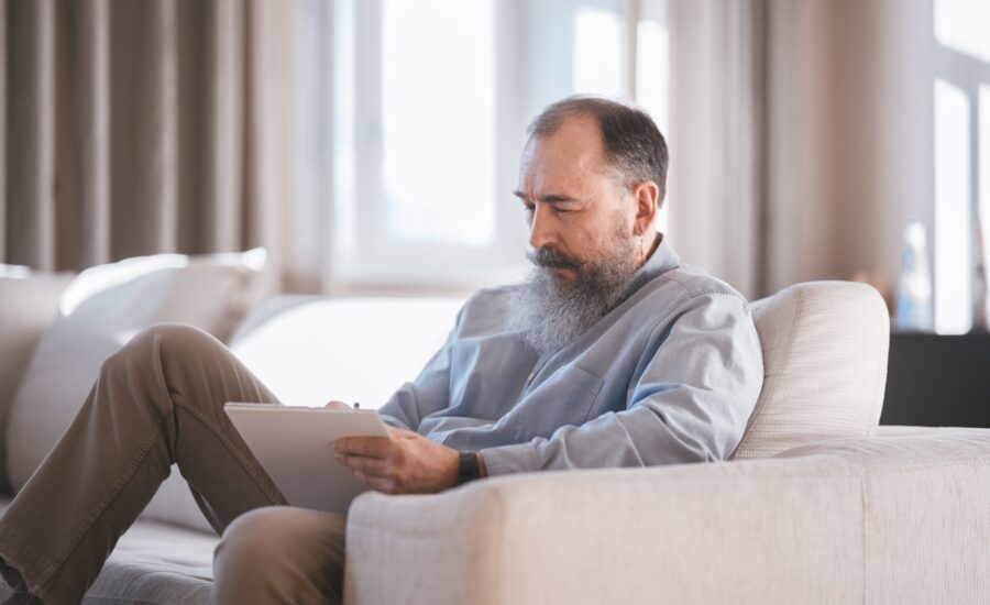 grey-haired man studying on couch