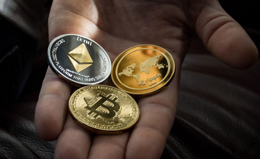 A hand holding coins with digital currencies on the faces