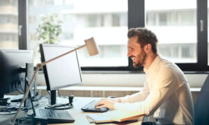 A man enthusiastically looking at his computer. It must be good news.