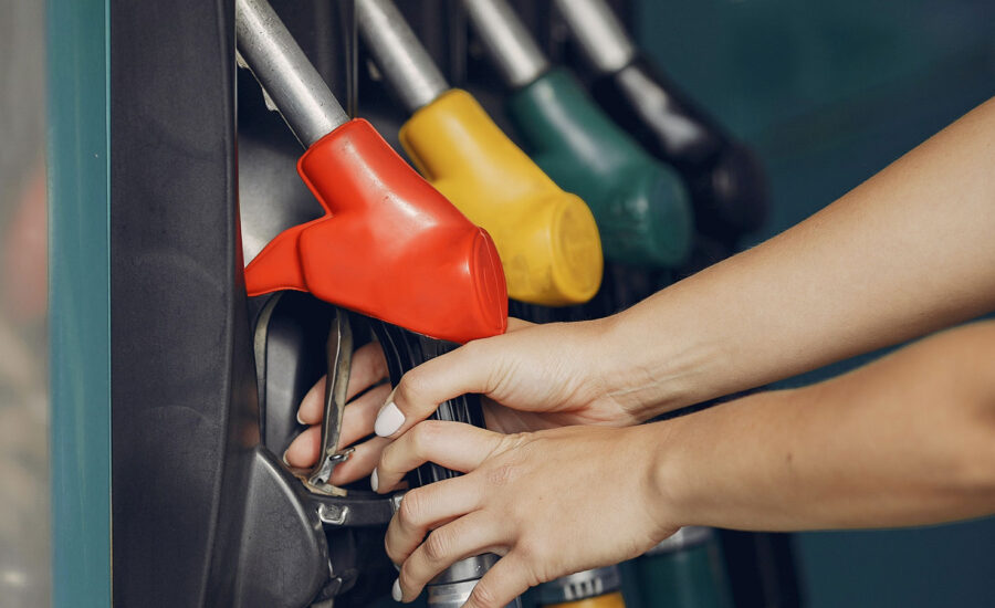 A pair of hands reaching for the gas pump at a station