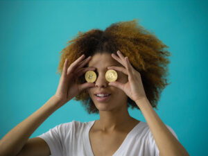 A woman is seen holding two coins to her eyes