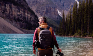 A man standing near the water at Lake Louise during his hike