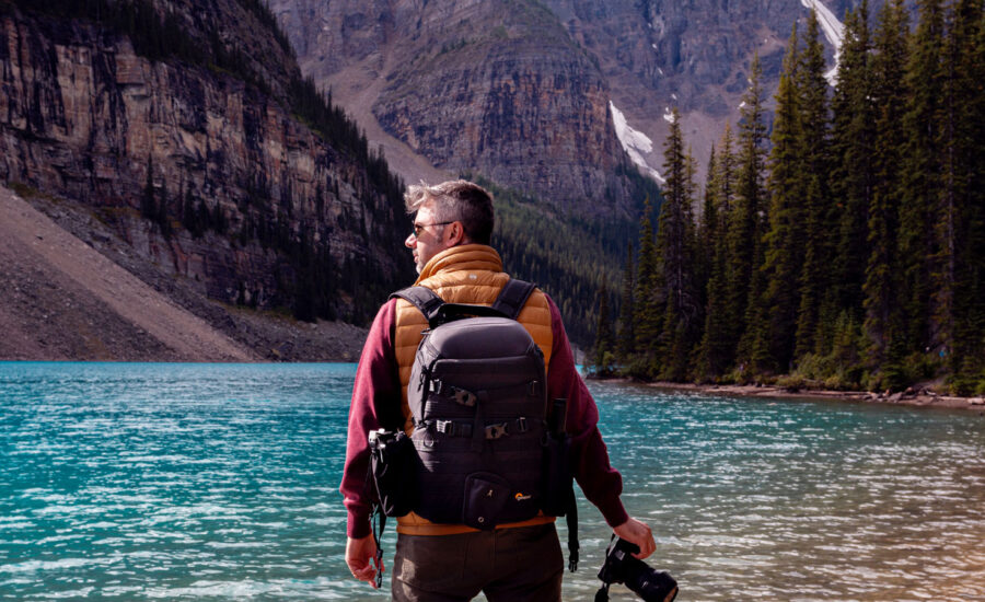 A man standing near the water at Lake Louise during his hike