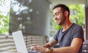 Smiling man using his laptop at a table.