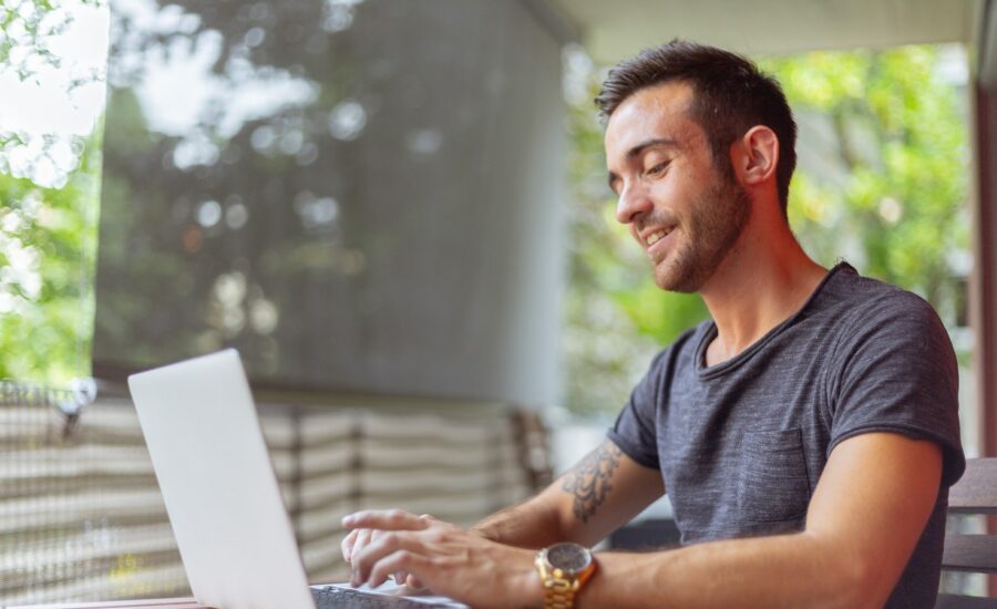 Smiling man using his laptop at a table.