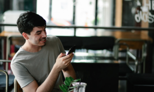 Man looking at smartphone and smiling in a restaurant