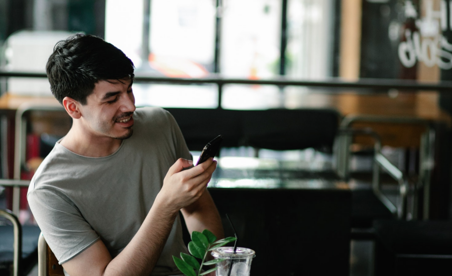 Man looking at smartphone and smiling in a restaurant