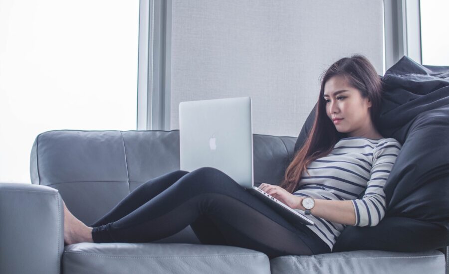 Woman reclining on a sofa and looking at her laptop