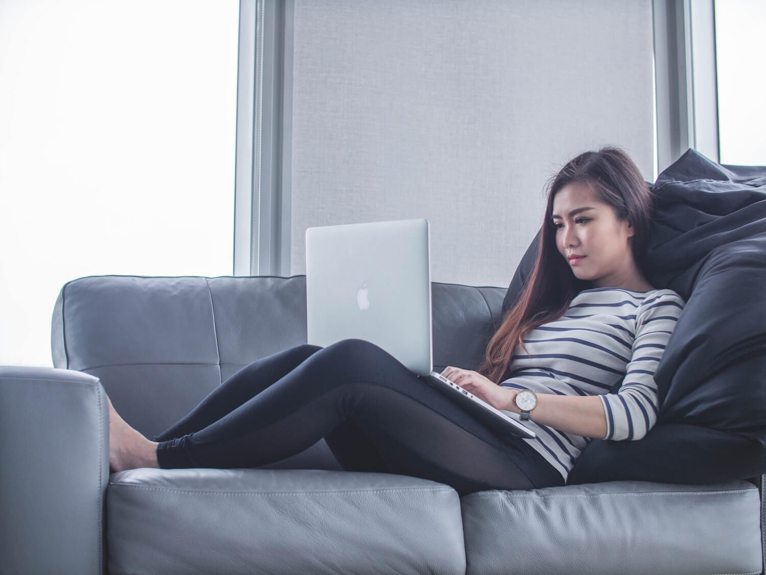 Woman reclining on a sofa and looking at her laptop