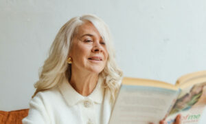 A 70-year-old woman sitting back reading a book