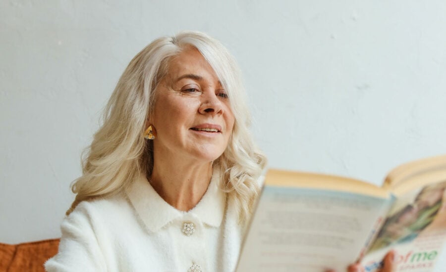 A 70-year-old woman sitting back reading a book