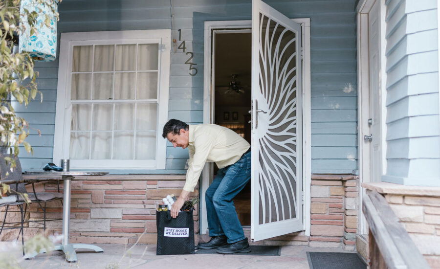 A man opens his door to find a bag of fresh food has been delivered to his front door.