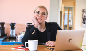 A woman at her desk, looking around, anywhere, except the task at hand, which is her taxes on her laptop.