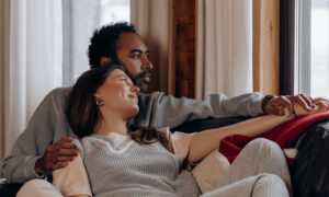 A couple sitting on their couch enjoying their home, as they look out the windwo