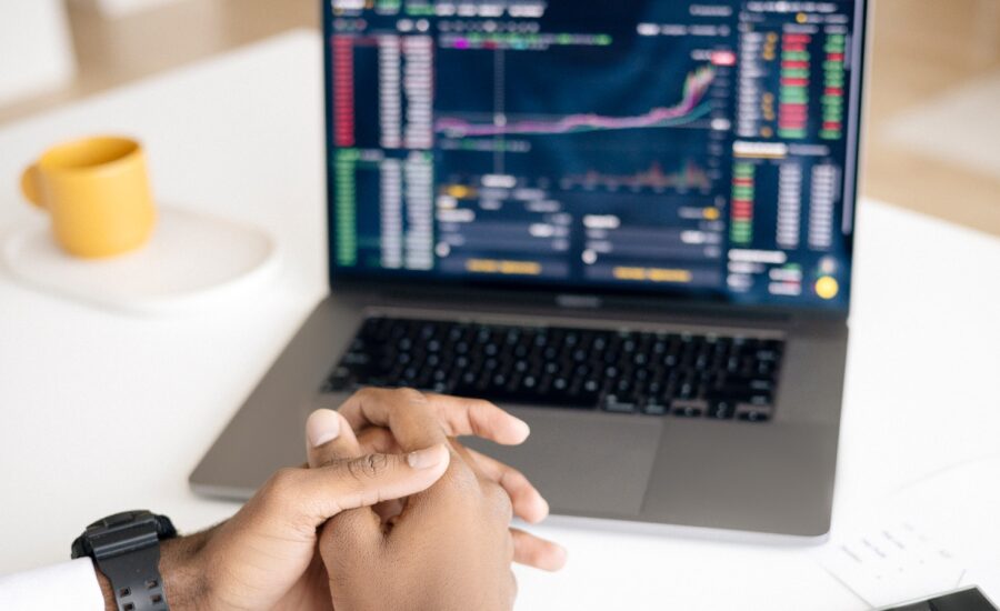 A pair of clasped hands in front of a laptop displaying a graph.