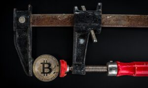 A gold bitcoin held in rusty calipers.