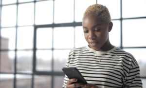 A woman looks down at her smartphone.