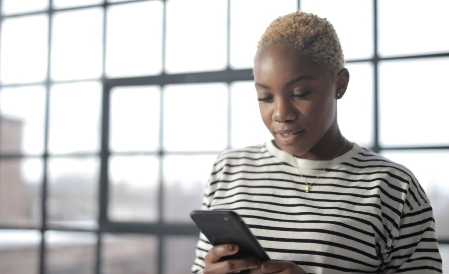 A woman looks down at her smartphone.