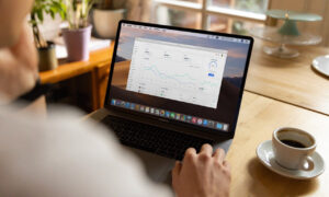 A person is seem sitting at a table working on a laptop