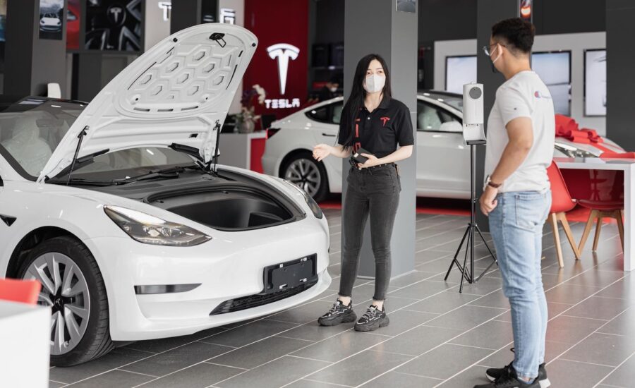 A photo of two people in a car dealership is seen standing by a white car