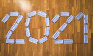 Surgical masks arranged to spell out 2021 on a hardwood floor.