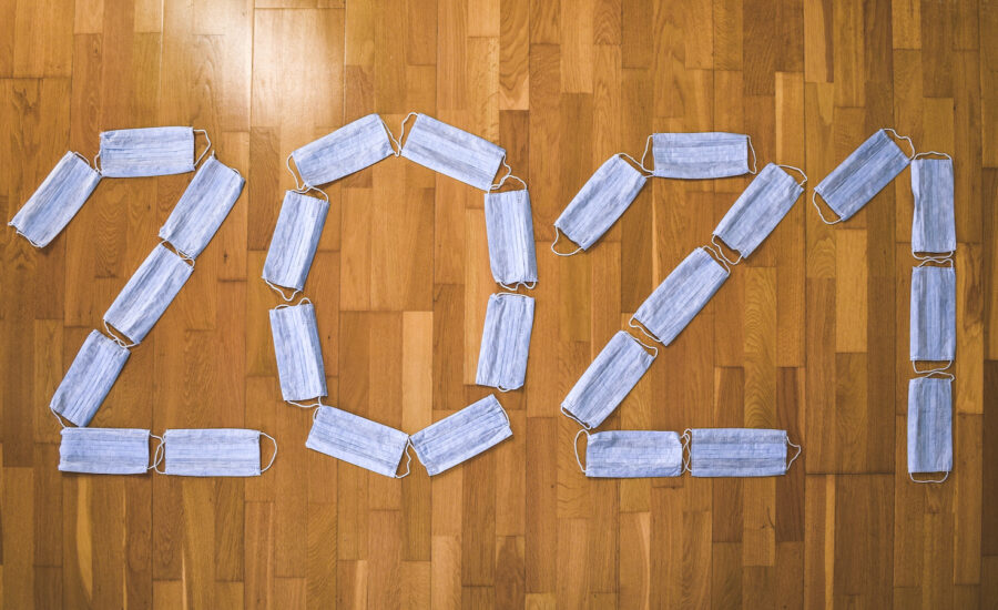 “Surgical masks arranged to spell out 2021 on a hardwood floor.