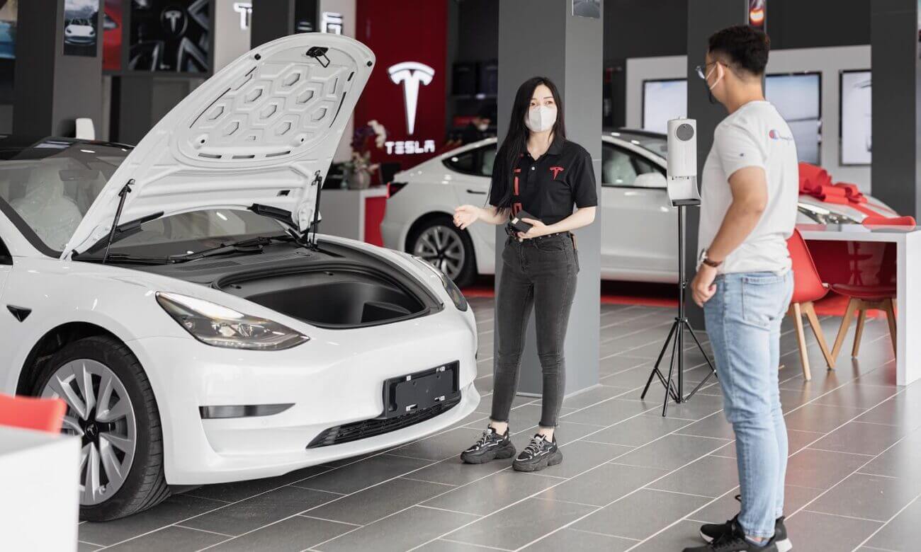A photo of two people in a car dealership is seen standing by a white car