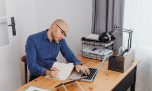 A man on a call, while sitting at his computer, trying to figure out if he should move his CPP into his RRSPs.