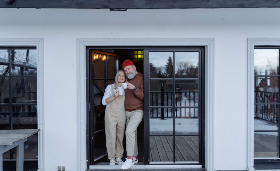 A senior-age couple outside their house