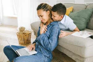 woman-looks-at-laptop-with-her-son-hugging-her