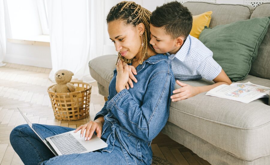 woman-looks-at-laptop-with-her-son-hugging-her