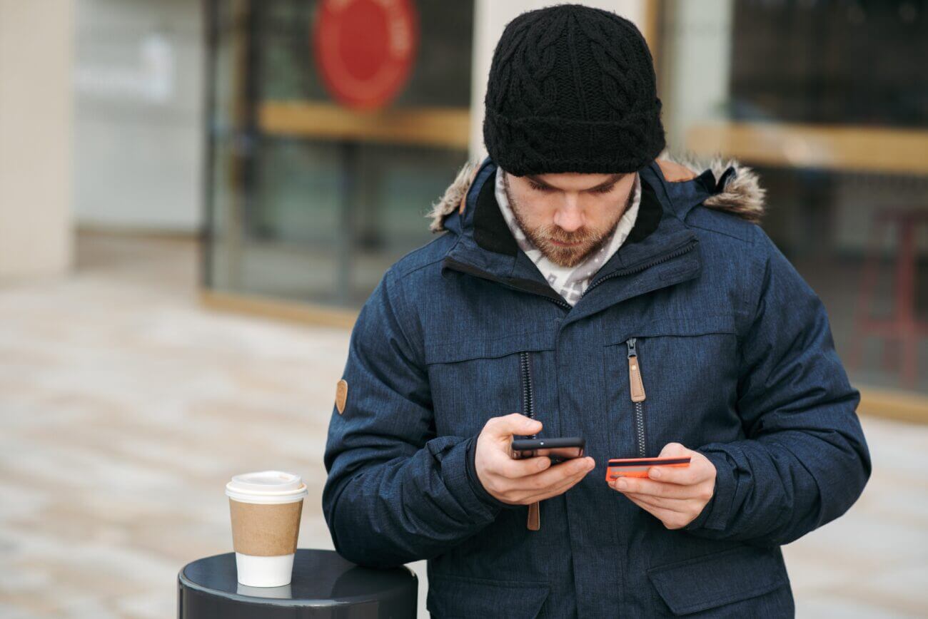 man-banking-on-his-phone-outside-in-winter