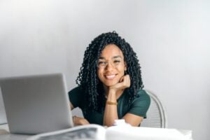 A young woman smiles as she compares different student credit cards online using her laptop