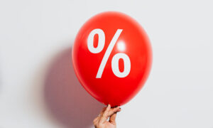 A woman's hand holds an inflated balloon with a % decal on it.