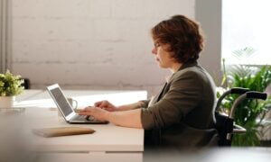 A woman uses her laptop while sitting at a desk