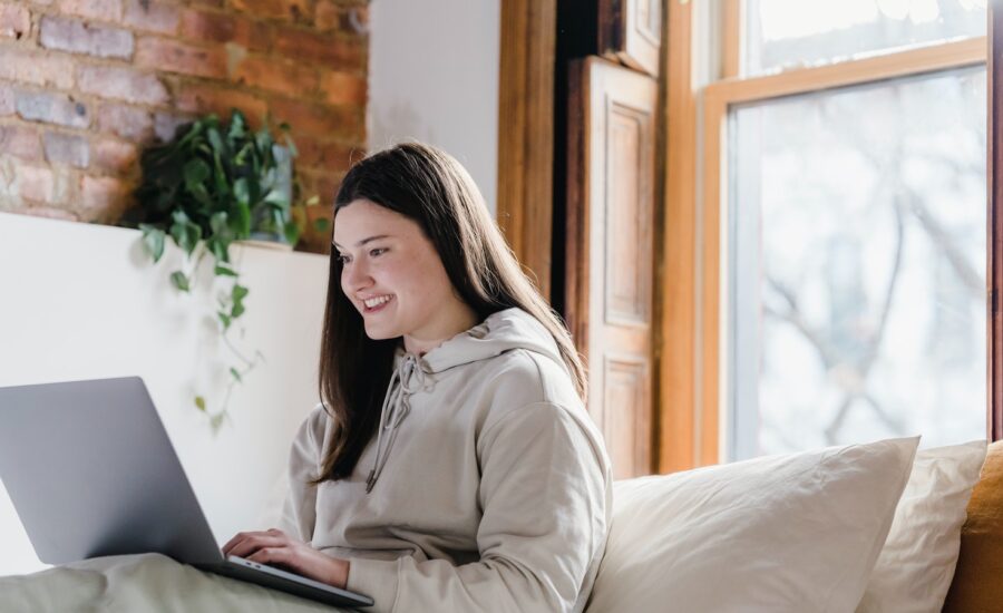 A smiling woman looks at her laptop.