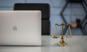 A image of a laptop set next to a scale is seen on a desk