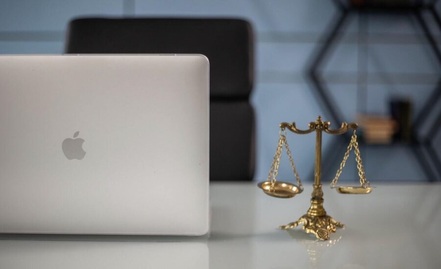 A image of a laptop set next to a scale is seen on a desk