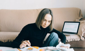 A woman is adding up receipts in her living room, as she prepares her information for her tax return