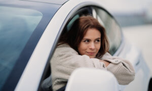 A woman leans out of her car window