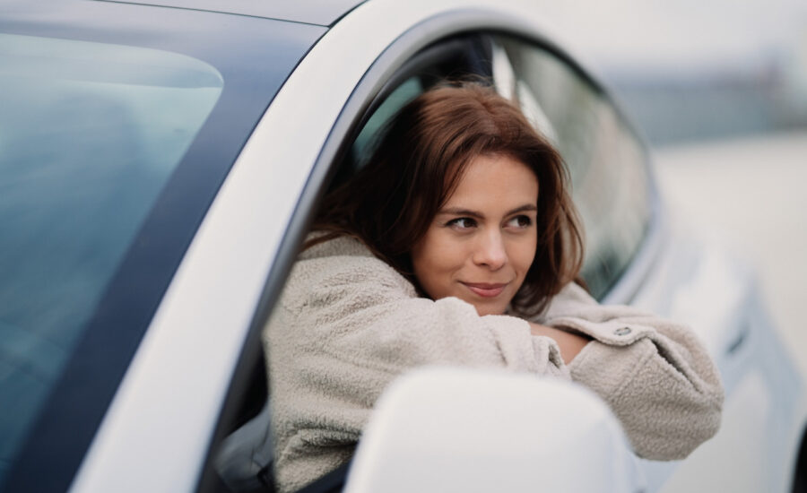A woman leans out of her car window