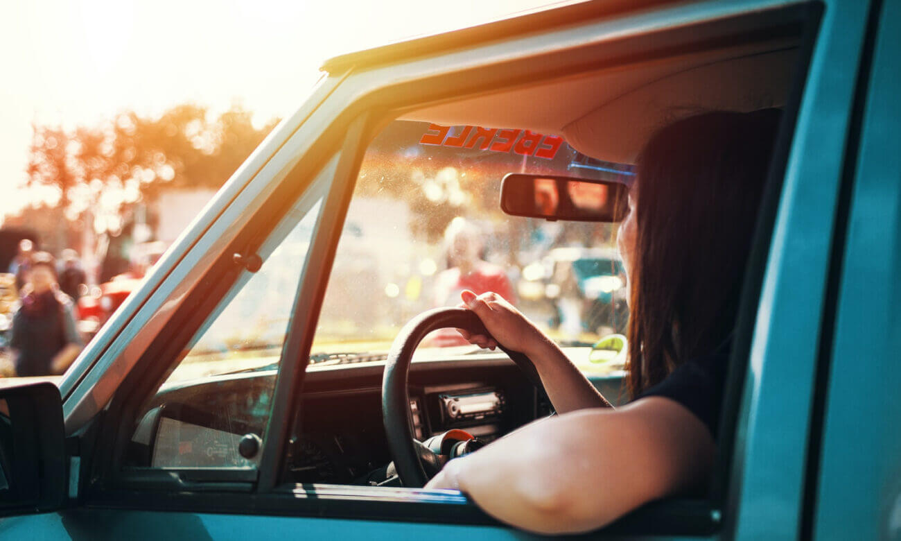 A woman sits in her vehicle with the window down