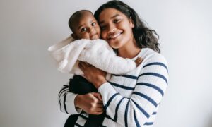 A smiling woman holds a baby